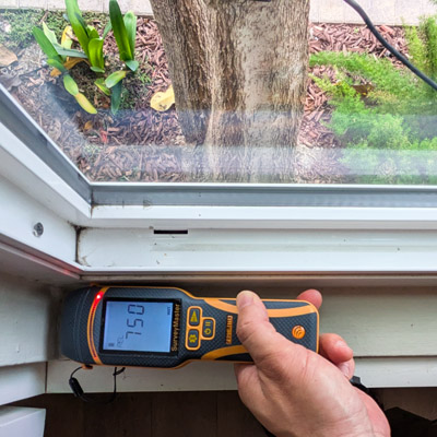 Tanjun Mold Inspections performing testing using Moisture Meter by Window.